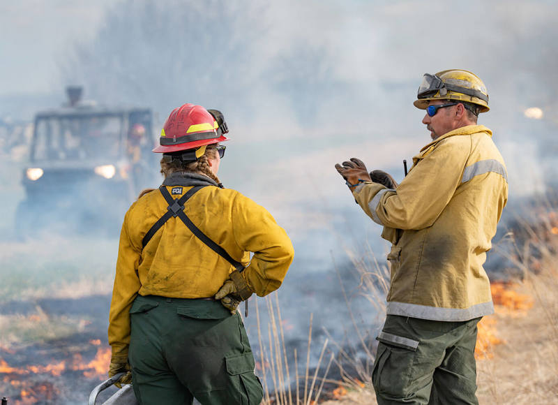 Burn workers talking in field during burn process