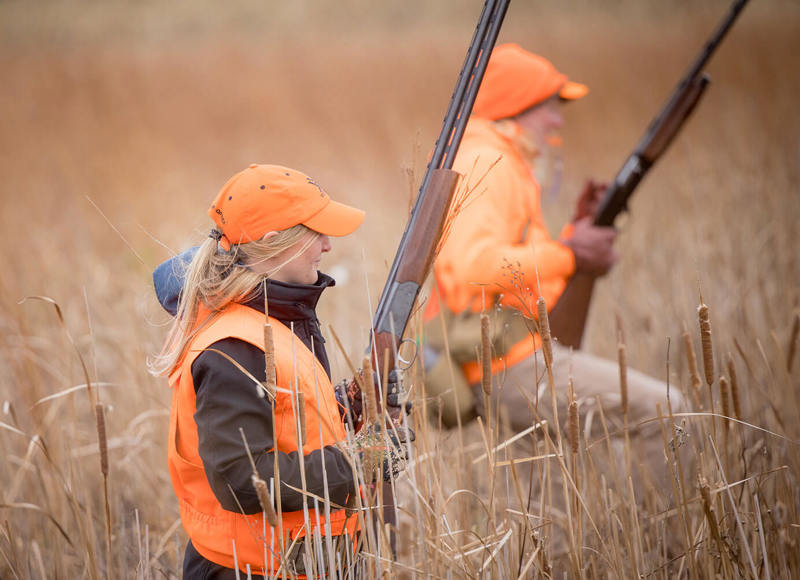 Two women hunters with guns in field