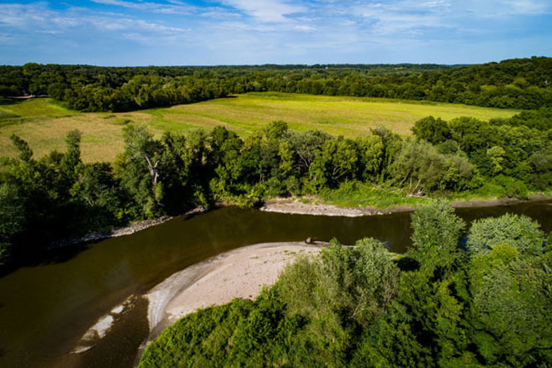 River with upland habitat, fields, trees, and blue sky